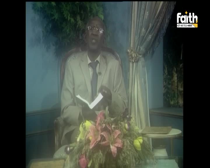 A man in a light suit and tie, holding an open book, speaks from his chair. A floral arrangement sits before him, and the Faith TV logo appears in the corner.