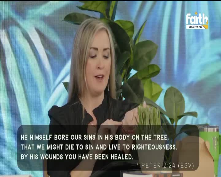 A woman speaks earnestly, her blonde hair framing her face as she gestures with her hands. Behind her, a vibrant green plant and a bright blue backdrop suggest a South African studio setting for Faith TV. A woman speaks earnestly, her blonde hair framing her face as she gestures with her hands. Behind her, a vibrant green plant and a bright blue backdrop suggest a South African studio setting for Faith TV.