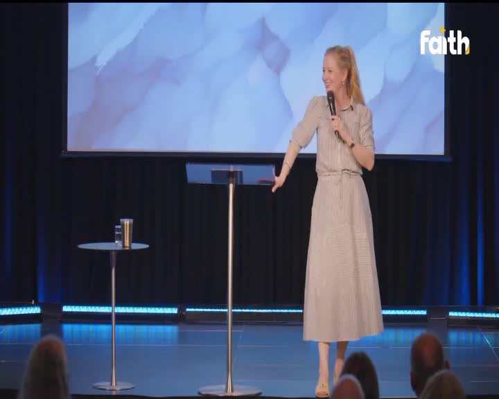 A woman in a striped dress speaks into a microphone on a stage, her left arm extended. The Faith TV logo appears in the upper right corner of the screen. A woman in a striped dress speaks into a microphone on a stage, her left arm extended. The Faith TV logo appears in the upper right corner of the screen.