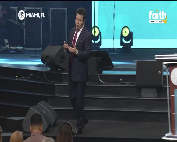 A man in a suit gestures with his hands as he speaks from a stage, the Faith TV logo visible on a screen behind him. The "Miami, FL" text indicates the broadcast location.