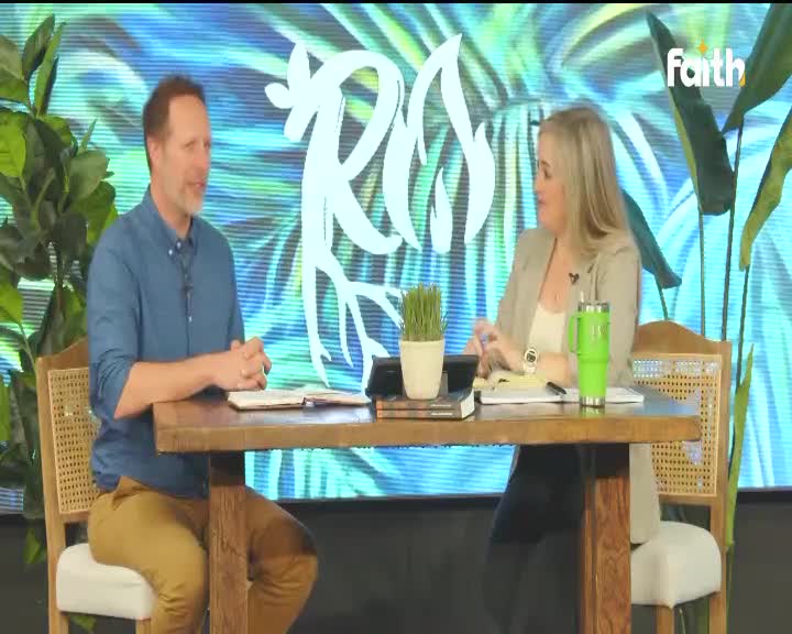 A man in a blue shirt and tan pants talks with a woman in a tan jacket. They sit at a wooden table with books and a green cup. The Faith TV logo appears on a screen behind them.