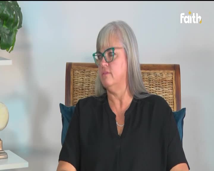 A woman with long, grey hair and teal-framed glasses sits in a wicker chair, looking slightly off-camera. The Faith TV logo appears in the top right corner of the screen.