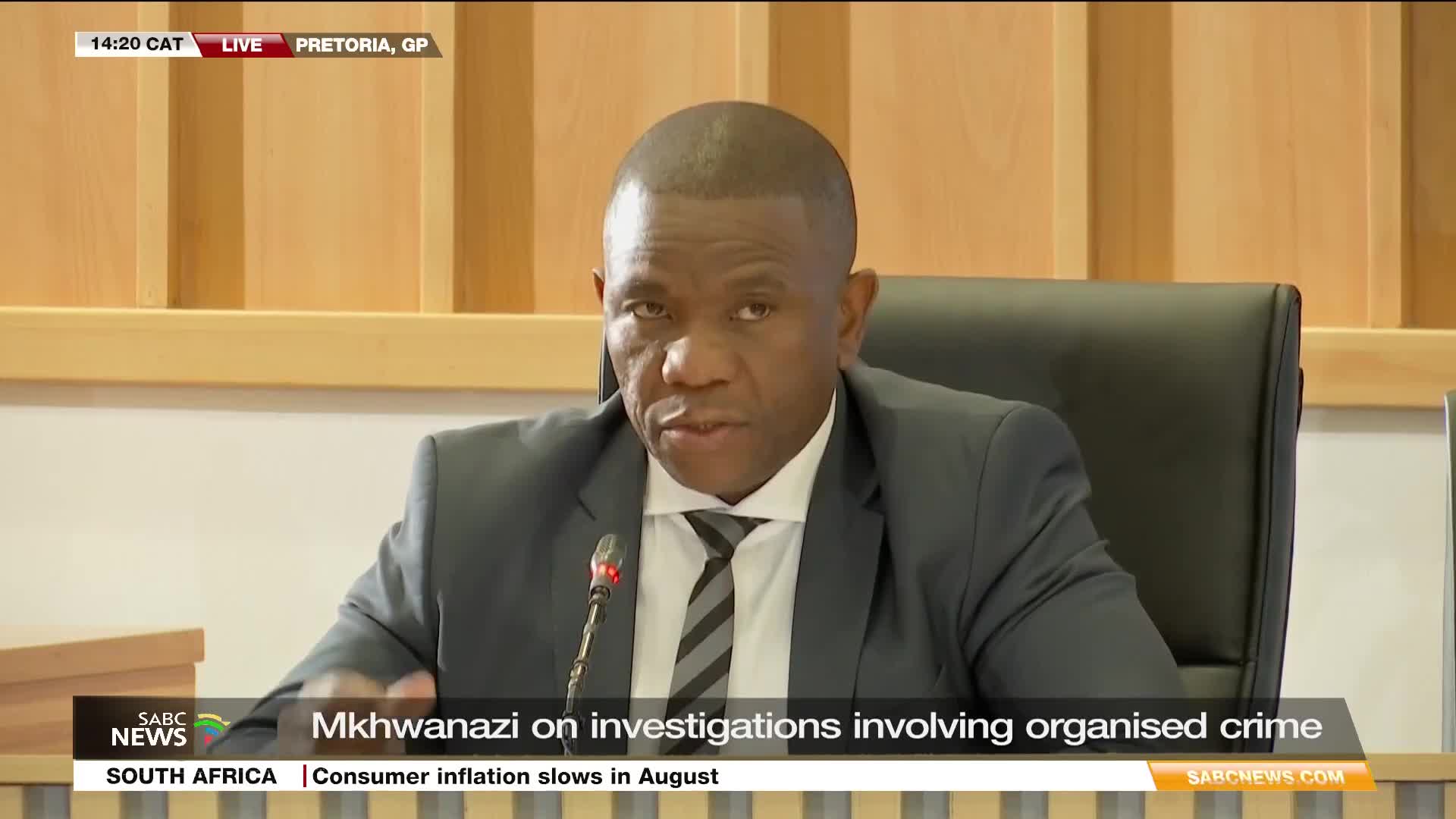 On SABC News, Mkhwanazi is speaking from Pretoria. He's wearing a suit and tie, addressing the camera about investigations into organised crime.
