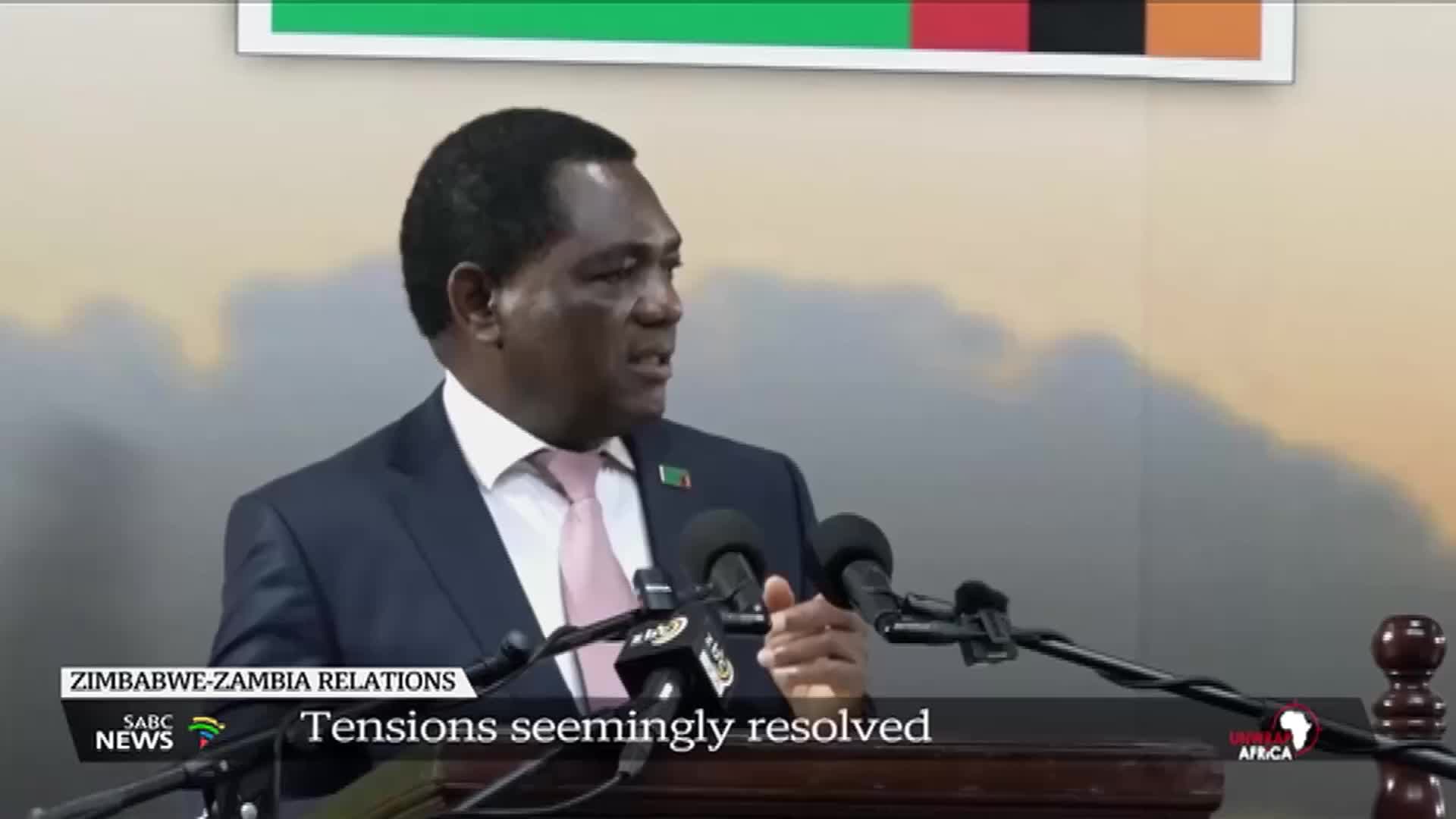 A man in a suit speaks into multiple microphones, his hands gesturing as he talks. SABC News' coverage of Zimbabwe-Zambia relations is underway, with the headline "Tensions seemingly resolved."
A man in a suit speaks into multiple microphones, his hands gesturing as he talks. SABC News' coverage of Zimbabwe-Zambia relations is underway, with the headline "Tensions seemingly resolved."