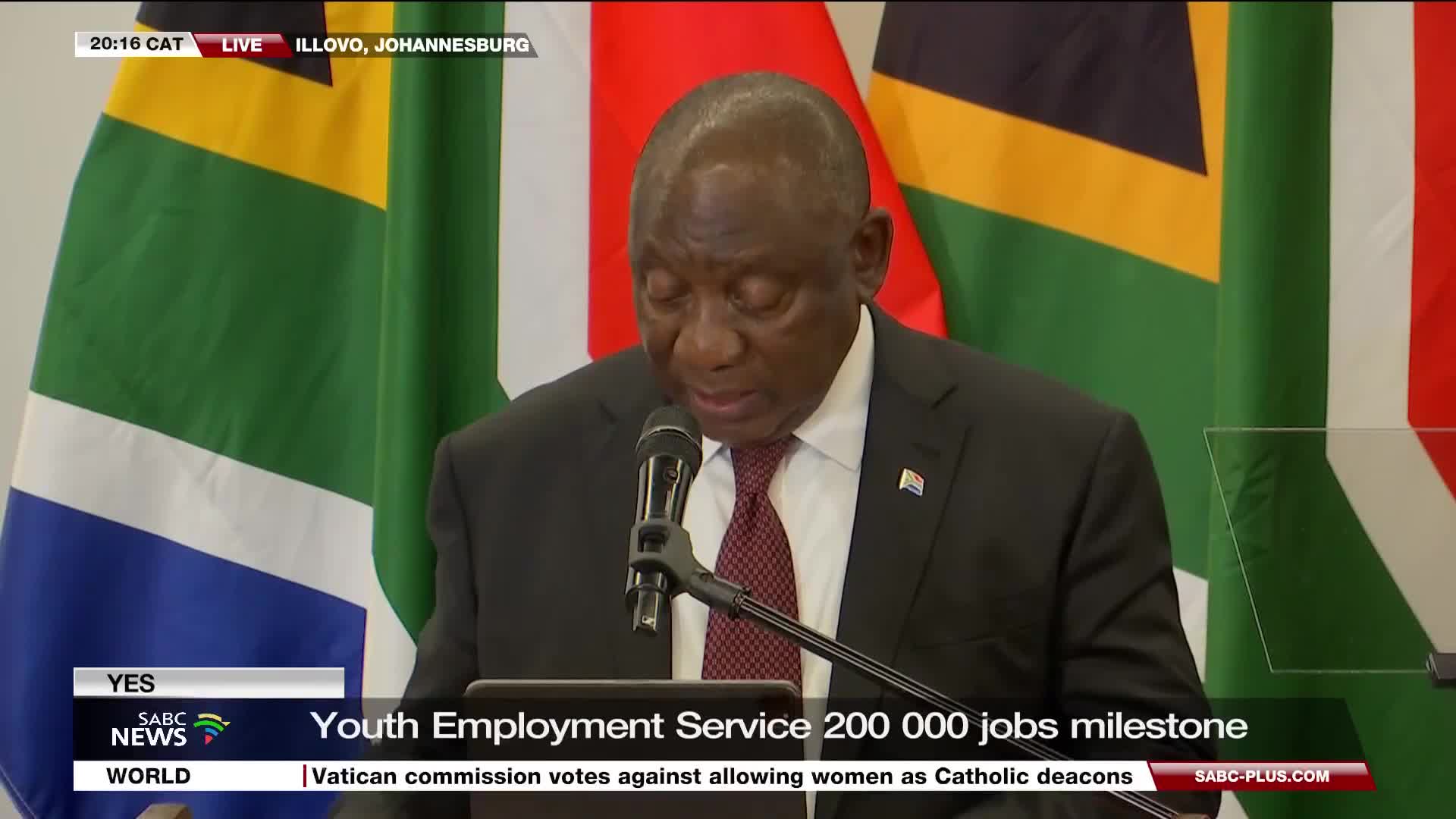 The president of South Africa, wearing a dark suit and a red tie, speaks into a microphone, his head bowed. Behind him, the South African flag and another, partially visible, wave gently.
The president of South Africa, wearing a dark suit and a red tie, speaks into a microphone, his head bowed. Behind him, the South African flag and another, partially visible, wave gently.