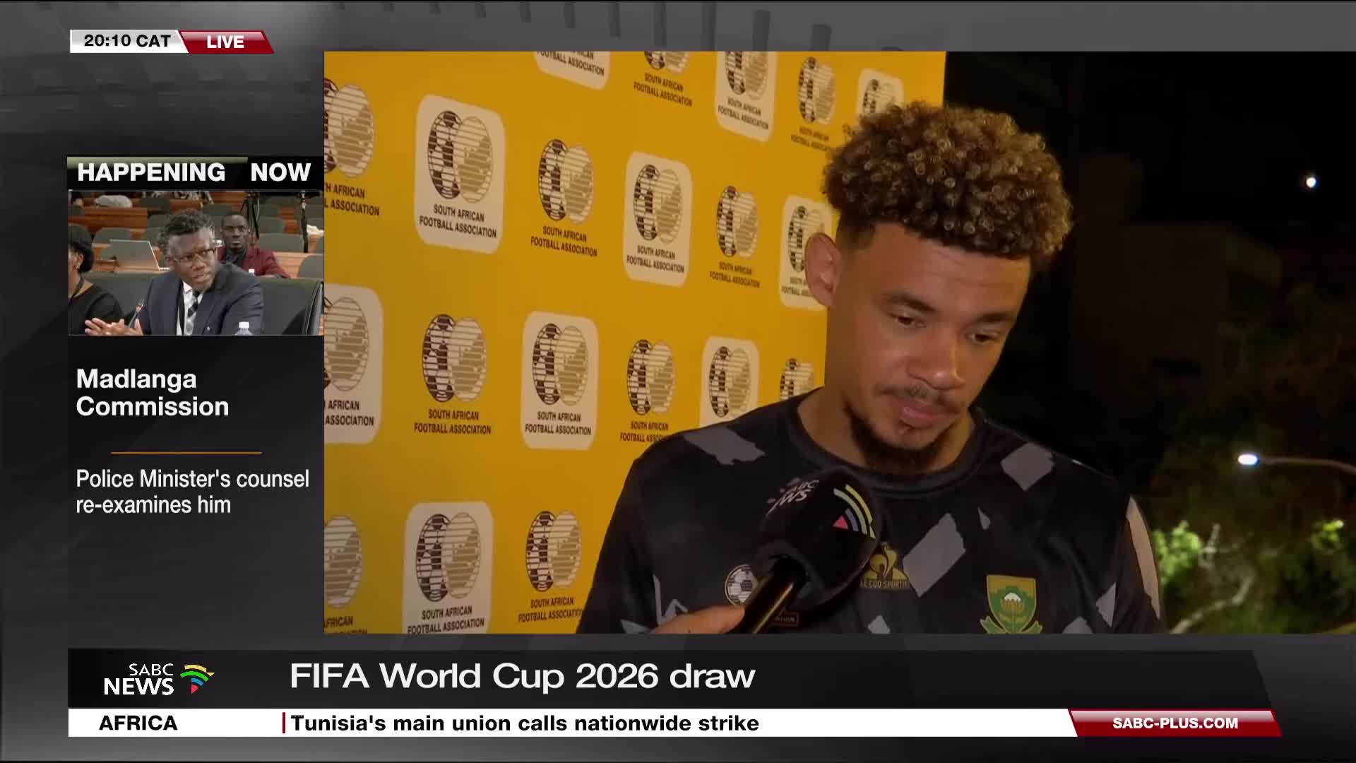 A man with curly hair speaks into a microphone, the South African Football Association logo behind him. SABC News is broadcasting live, with a segment on the Madlanga Commission happening in a smaller window.
A man with curly hair speaks into a microphone, the South African Football Association logo behind him. SABC News is broadcasting live, with a segment on the Madlanga Commission happening in a smaller window.