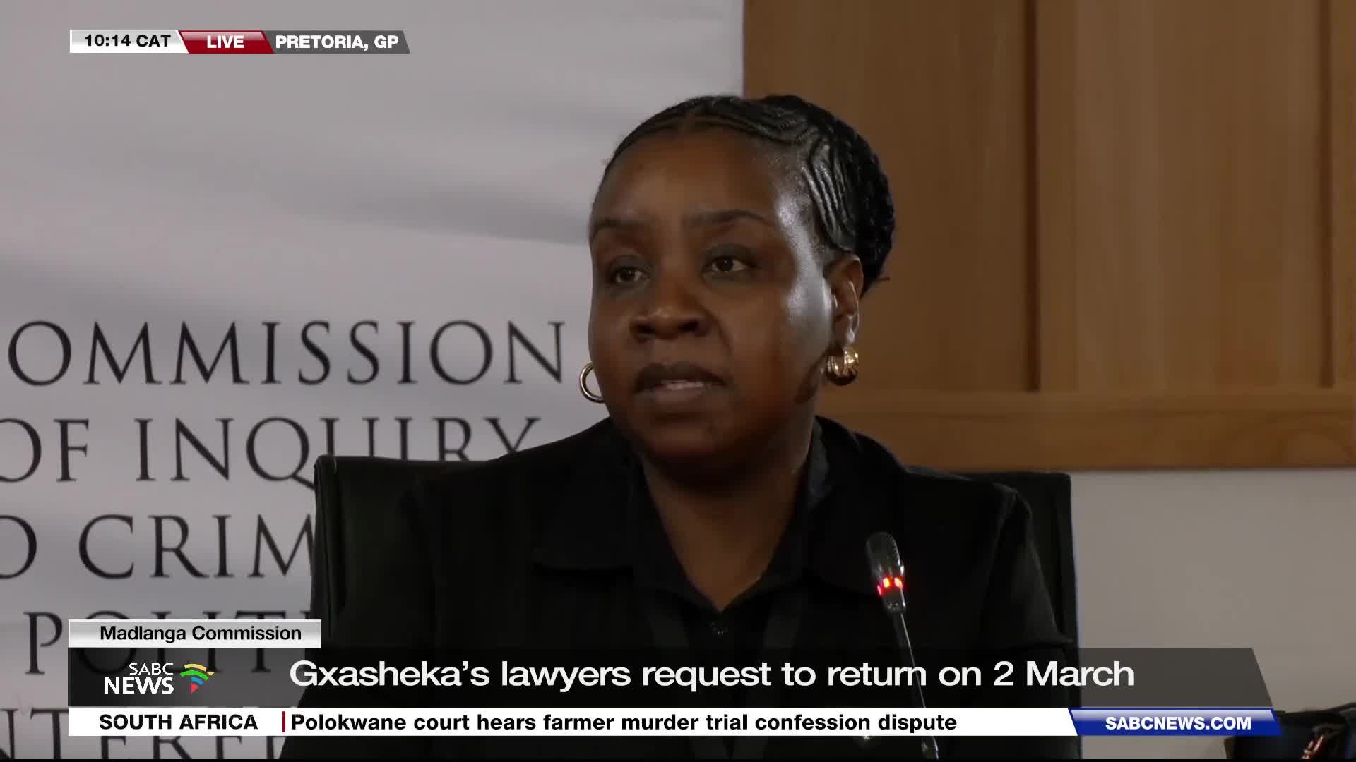 A woman in a black suit speaks into a microphone at a commission of inquiry. The SABC News chyron indicates Gxasheka's lawyers are requesting a return date of March 2nd. A woman in a black suit speaks into a microphone at a commission of inquiry. The SABC News chyron indicates Gxasheka's lawyers are requesting a return date of March 2nd.