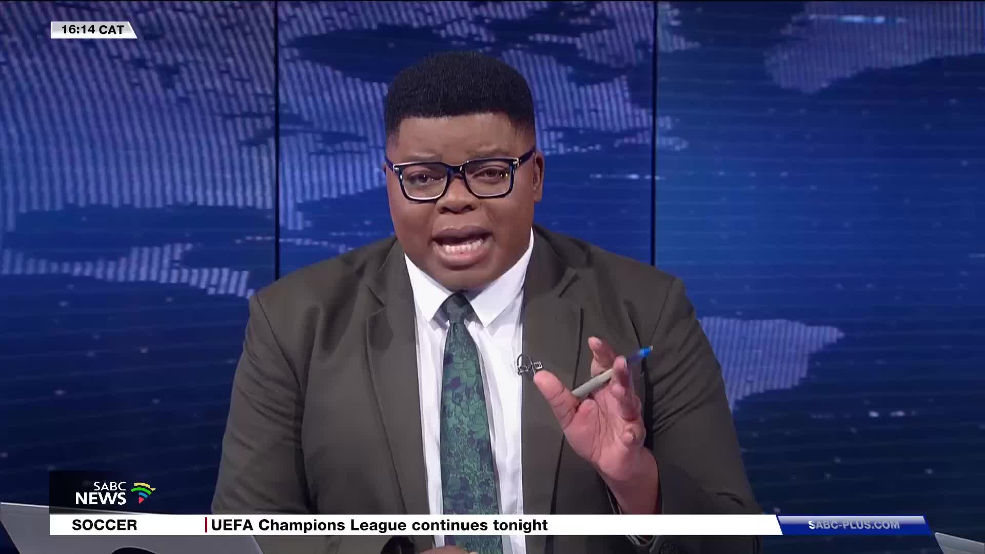 A presenter, dressed in a suit and tie, speaks with conviction, gesturing with a pen. The SABC News logo is visible in the corner, alongside the time 16:14 CAT.