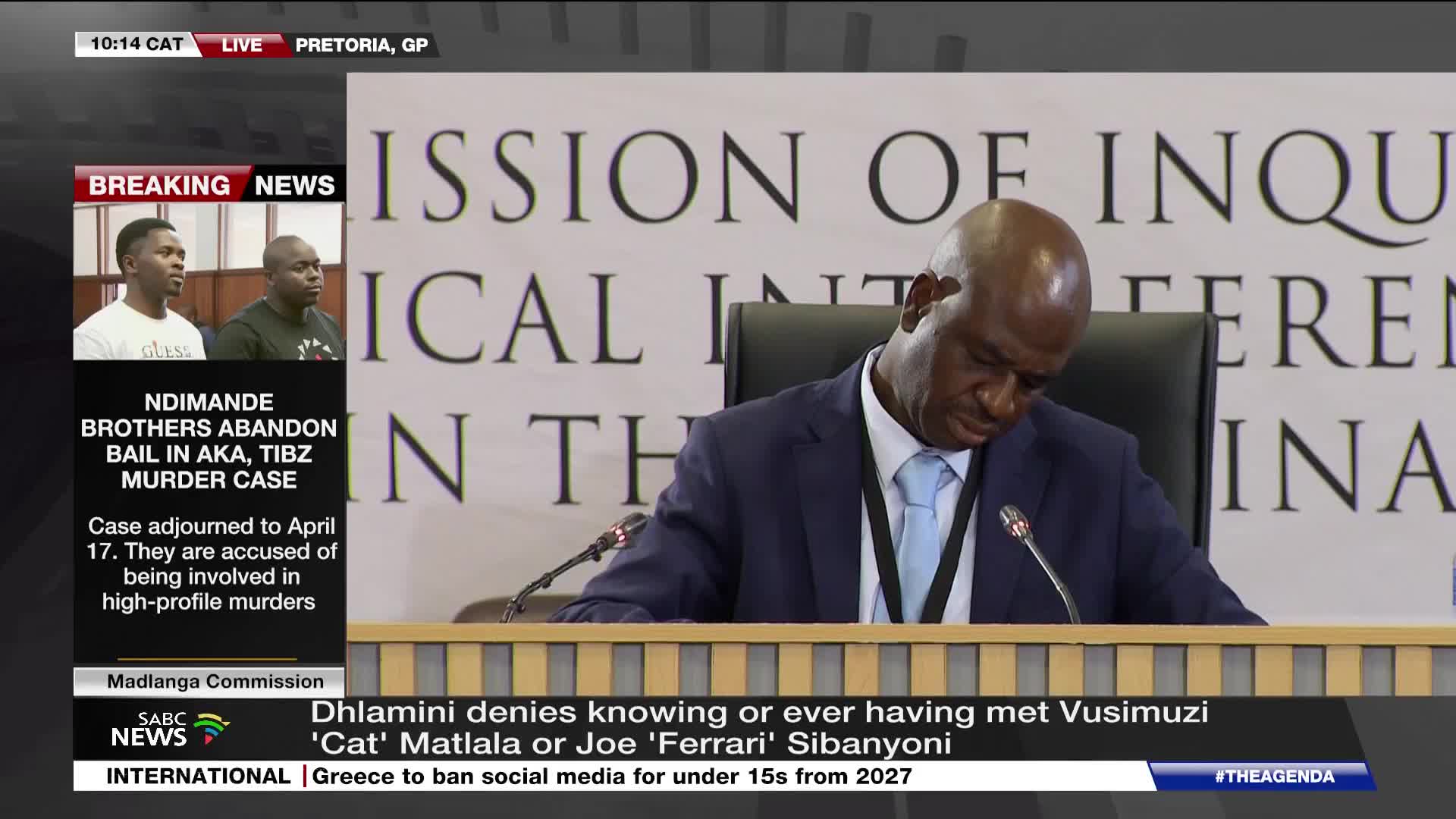 A man in a suit leans forward, his head bowed. Behind him, large lettering reads "COMMISSION OF INQUIRY."