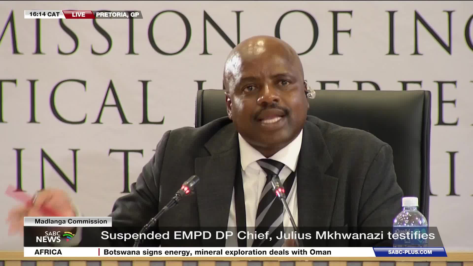 A man in a suit and tie speaks into a microphone, his hand gesturing slightly. The SABC News banner at the bottom of the screen identifies him as Julius Mkhwanazi, testifying at the Madlanga Commission.