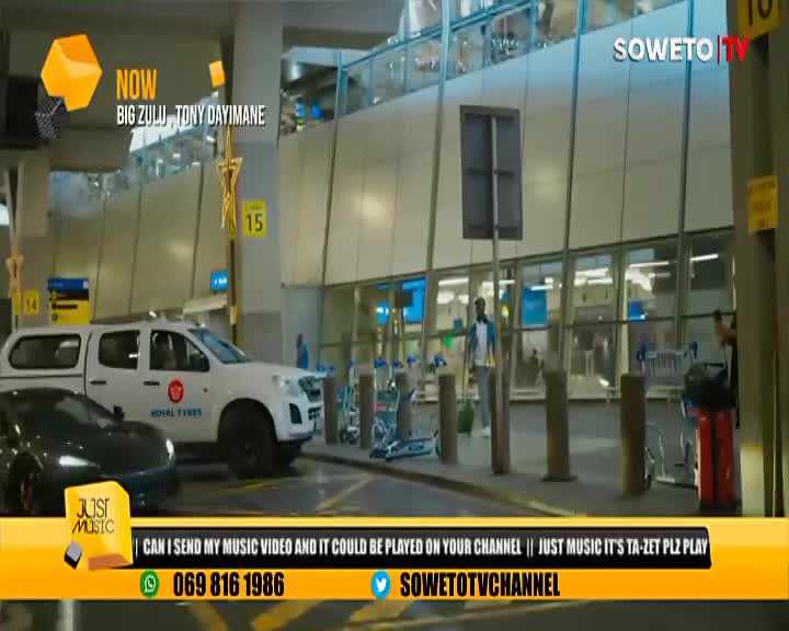 A white pickup truck with "Royal Tyres" is parked near the entrance, next to a black car. A man in a blue shirt walks toward the glass doors, while the Soweto TV logo sits in the corner.
