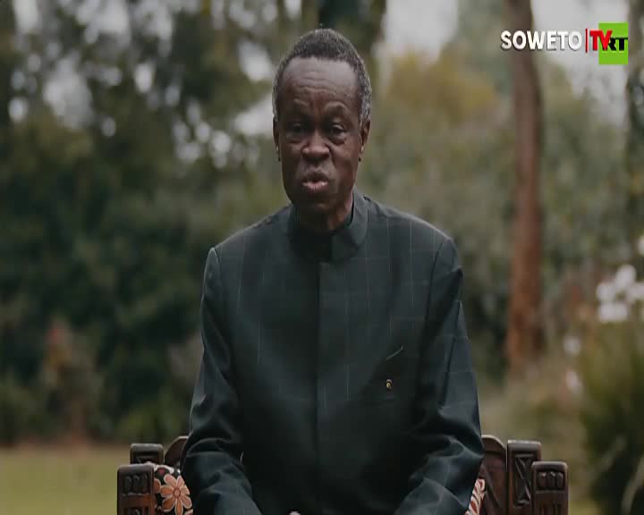 A man in a dark suit sits on a bench, speaking directly to the camera. The Soweto TV logo is visible in the top right corner.
