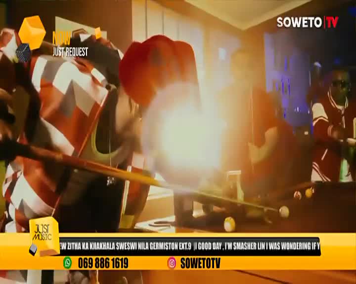 A bright flash erupts near a pool table, obscuring the players on the Soweto TV set. The cue stick is poised, ready to strike the cue ball.
