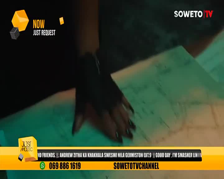 A hand with long, dark fingernails rests on a piece of paper, likely a map, with the Soweto TV logo in the corner. The "Just Music" request segment is playing, and the phone number is visible at the bottom.
