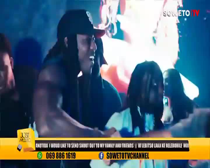 A man in a black cap is singing, his face lit up with energy, while others stand around him. The Soweto TV logo and a scrolling message are visible at the bottom of the screen.
