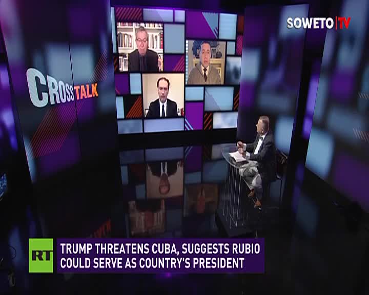 A man in a suit sits at a glass desk, facing a screen displaying multiple video feeds. The Soweto TV logo is visible in the background.