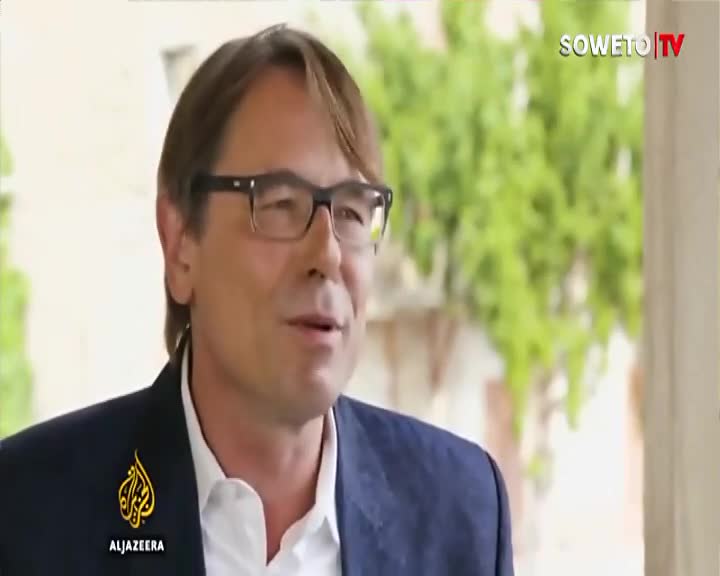 A man in a dark blazer and white shirt speaks, his glasses reflecting the light. The Soweto TV logo appears in the upper right corner. A man in a dark blazer and white shirt speaks, his glasses reflecting the light. The Soweto TV logo appears in the upper right corner.