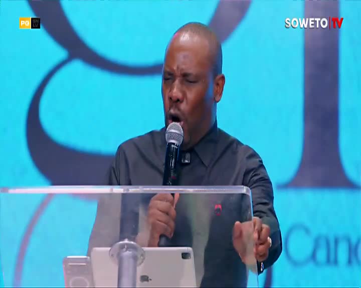 A man speaks into a microphone, his eyes closed and his mouth open in a passionate expression. The Soweto TV logo is visible in the corner of the bright blue background. A man speaks into a microphone, his eyes closed and his mouth open in a passionate expression. The Soweto TV logo is visible in the corner of the bright blue background.