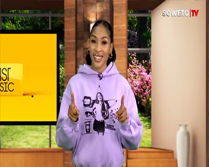 A woman in a lilac hoodie stands on a Soweto TV set, gesturing with both hands. A bright yellow screen behind her displays "CHRIST MUSIC."