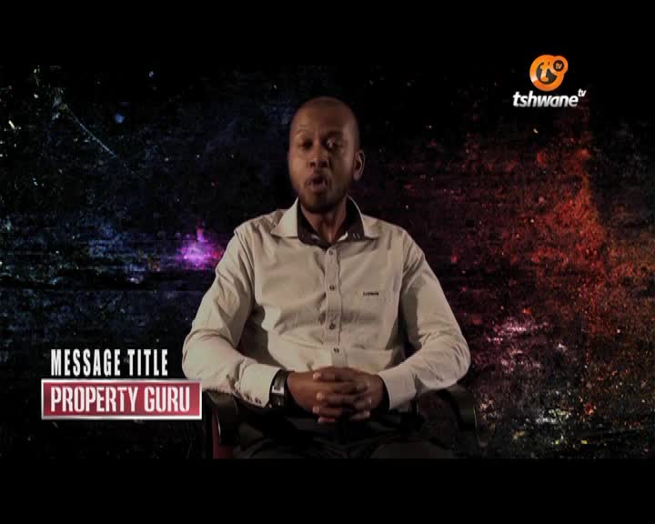 A man in a button-down shirt is speaking, likely on Tshwane TV in South Africa, his hands clasped in his lap. The words "Property Guru" appear below him, suggesting the topic of discussion.
