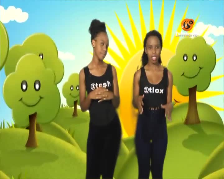Two women are standing in front of a cartoon backdrop, both wearing black tops and pants. They're on Tshwane TV, and the one on the right is gesturing with her hands as she speaks.
