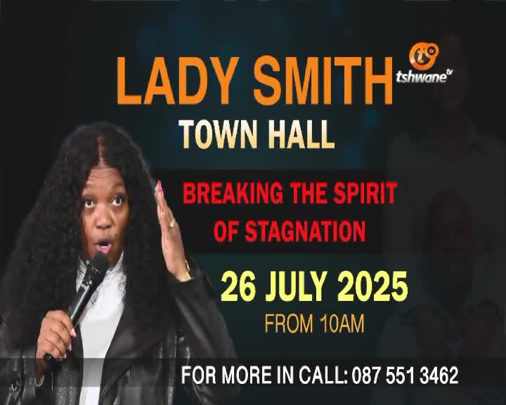 A woman with dark, curly hair gestures with her right hand while speaking into a microphone, framed by a Tshwane TV graphic. The screen advertises a "Lady Smith Town Hall" event in July 2025, promising to break the spirit of stagnation.
