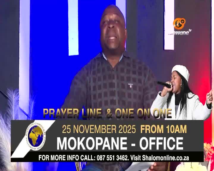 A man in a checkered shirt addresses the camera, while a woman sings into a microphone to his right. The Tshwane TV logo sits at the top right, with a promotional banner for a prayer line below.
A man in a checkered shirt addresses the camera, while a woman sings into a microphone to his right. The Tshwane TV logo sits at the top right, with a promotional banner for a prayer line below.