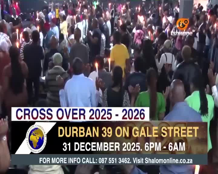 Candlelight flickers above a crowd gathered for a service, as the Tshwane TV broadcast shows a banner promoting a Durban event. Many people raise their hands, some holding lit candles, during the "Cross Over" event.
