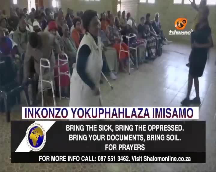 A woman in a white vestment strides forward, gesturing as if to address the seated crowd. The Tshwane TV logo sits in the top right corner, broadcasting the event.
