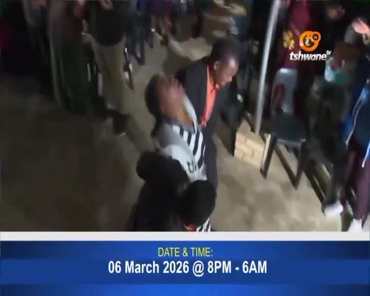 A man in a suit leans over, his face in his hands, while another man in a striped shirt is held upright by someone behind him. The Tshwane TV logo is visible in the background. A man in a suit leans over, his face in his hands, while another man in a striped shirt is held upright by someone behind him. The Tshwane TV logo is visible in the background.