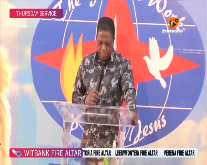A man stands behind a clear podium, holding a microphone. The backdrop behind him features a large red star with flames and a white dove, along with the Tshwane TV logo. A man stands behind a clear podium, holding a microphone. The backdrop behind him features a large red star with flames and a white dove, along with the Tshwane TV logo.
