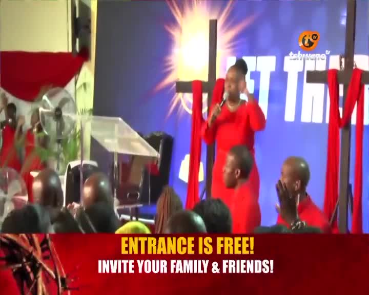A woman in a red dress speaks into a microphone, her hands gesturing. Behind her, red fabric drapes across crosses, and a bright light emanates from the backdrop. A woman in a red dress speaks into a microphone, her hands gesturing. Behind her, red fabric drapes across crosses, and a bright light emanates from the backdrop.