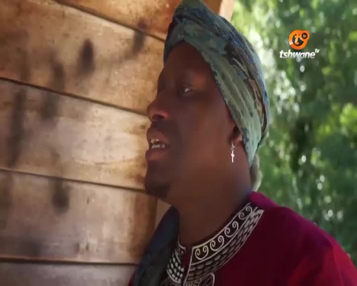 A man with a patterned headscarf and a cross earring speaks, his maroon garment adorned with intricate white swirls. The Tshwane TV logo appears in the upper right corner, hinting at a broadcast from South Africa. A man with a patterned headscarf and a cross earring speaks, his maroon garment adorned with intricate white swirls. The Tshwane TV logo appears in the upper right corner, hinting at a broadcast from South Africa.