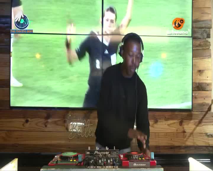 A DJ with headphones on is working his equipment in front of a large screen showing a rugby match. The screen displays the Tshwane TV logo and a snippet of a game, possibly from the Springboks' recent matches.