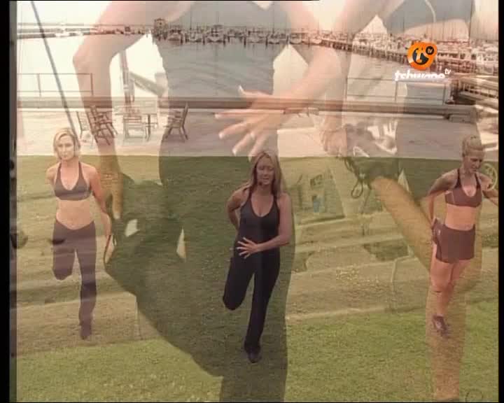 Three women are stretching their legs on a grassy area. The Tshwane TV logo is visible in the upper right corner.