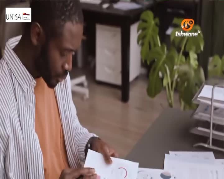 A man in a striped shirt leans over a desk, examining a document. The Tshwane TV logo is visible in the background.