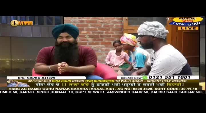 A man with a long beard and a turban sits on a set, speaking to the camera. Beside him, two men and a young girl are seated, likely part of a segment on the Akaal Channel from the United Kingdom.
