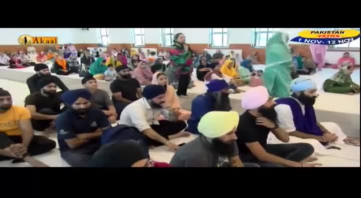 People are seated on the floor, listening to a speaker. The event is being broadcast on Akaal Channel, with a banner advertising a Pakistan Yatra.
