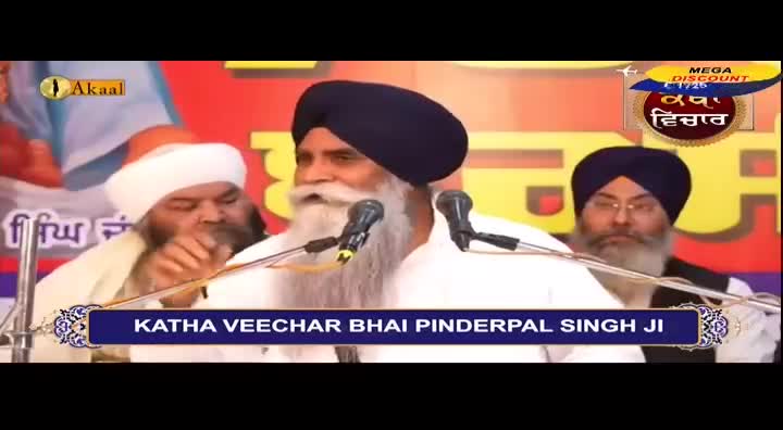 A man with a long white beard speaks into a microphone, his words broadcast on Akaal Channel. Two other men in turbans sit beside him, listening intently.
