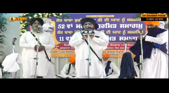 Three men in turbans and white robes stand at microphones, speaking before a banner that reads "350 Shaheedi Purab." The scene is being broadcast on Akaal Channel.
