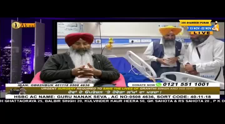 A man with a red turban sits in a chair, speaking on a broadcast from Akaal Channel. Two other men in turbans stand near a hospital bed, appearing to be in a medical setting.
