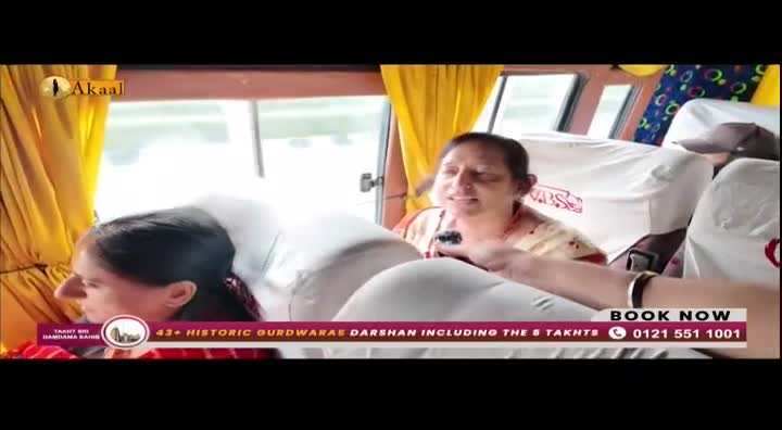 Inside a bus, a woman speaks, holding a microphone, while another woman sits beside her, looking ahead. The scene is being broadcast on Akaal Channel, with a booking advertisement at the bottom.
