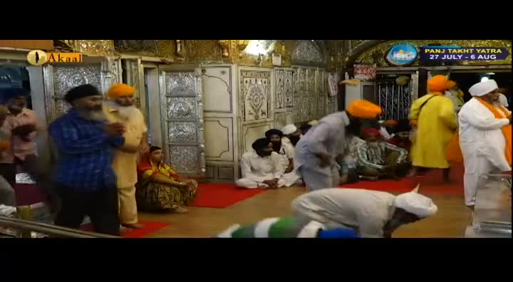 Men in turbans are gathered inside a building, some bowing their heads. The Akaal Channel logo is visible in the upper left corner, indicating this is a broadcast from the United Kingdom.