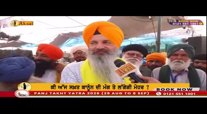 A man with a long white beard and an orange turban speaks into an Akaal microphone. He's surrounded by other men, some also wearing turbans, in what appears to be an outdoor gathering. A banner at the bottom announces "PANJ TAKHT YATRA 2026."