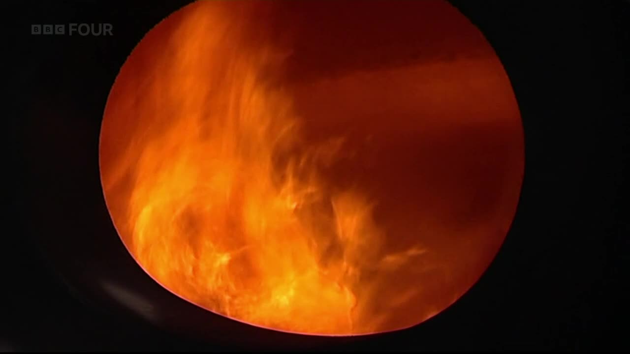 A fiery, swirling mass fills the circular frame, its bright orange hues contrasting sharply with the surrounding black. It looks like something burning intensely, maybe from a BBC Four program.
