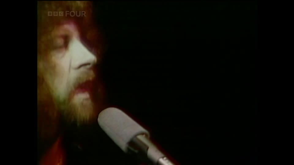 A man with a beard sings into a microphone, his face lit by a warm glow. The BBC Four logo appears in the top left corner.