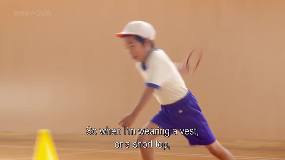 A young person in athletic wear is running past a yellow cone, their arm blurred from movement. This is part of a segment on BBC Four, likely showing a school sports day.