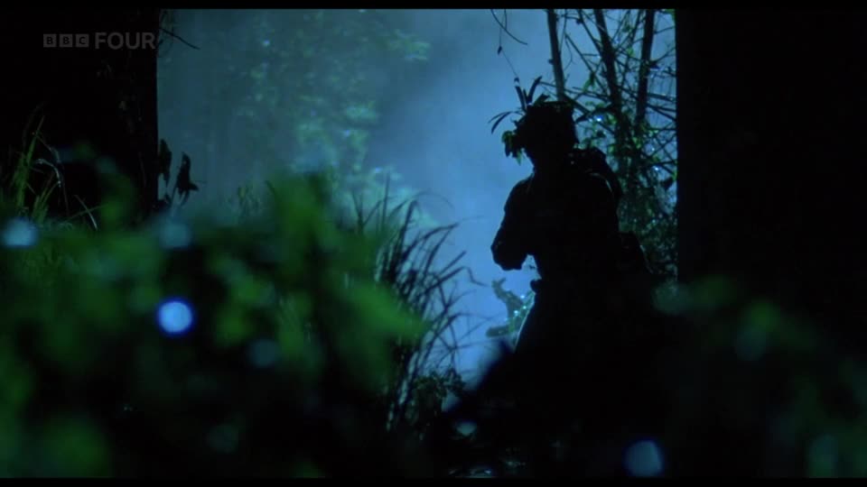 A figure, silhouetted against a misty, blue-tinged background, moves through dense foliage. The BBC Four logo is visible in the top left corner, suggesting this is a scene from a British broadcast.