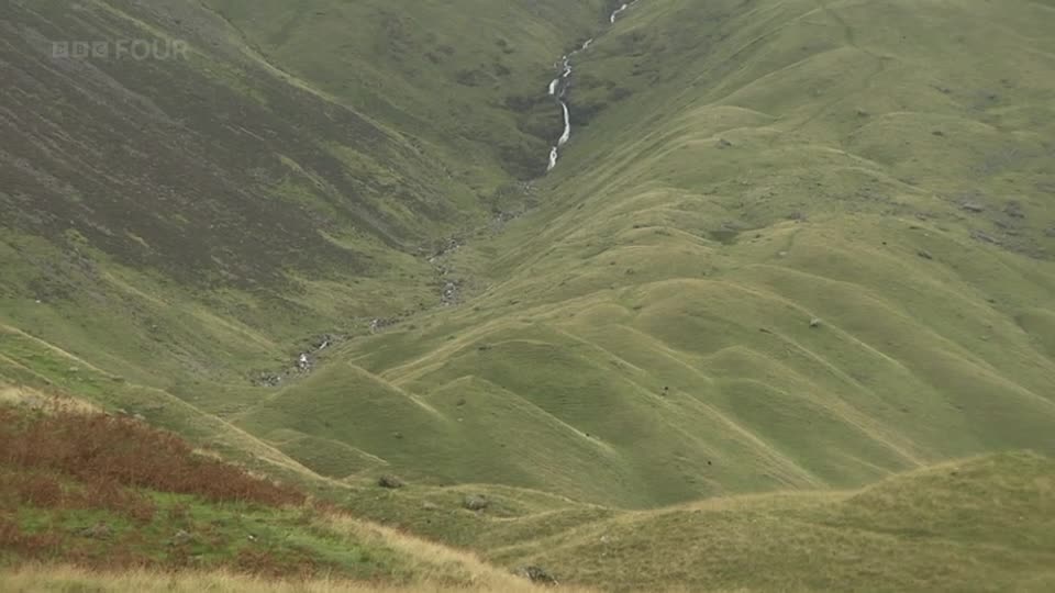 A thin ribbon of water cascades down the steep, green hillside. The rolling landscape, typical of the United Kingdom, stretches out before me, bathed in the soft light that BBC Four often captures so well.