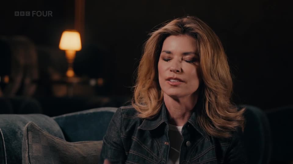 A woman with blonde hair sits on a plush sofa, a BBC Four logo visible in the corner. She speaks with her eyes closed, her expression thoughtful.